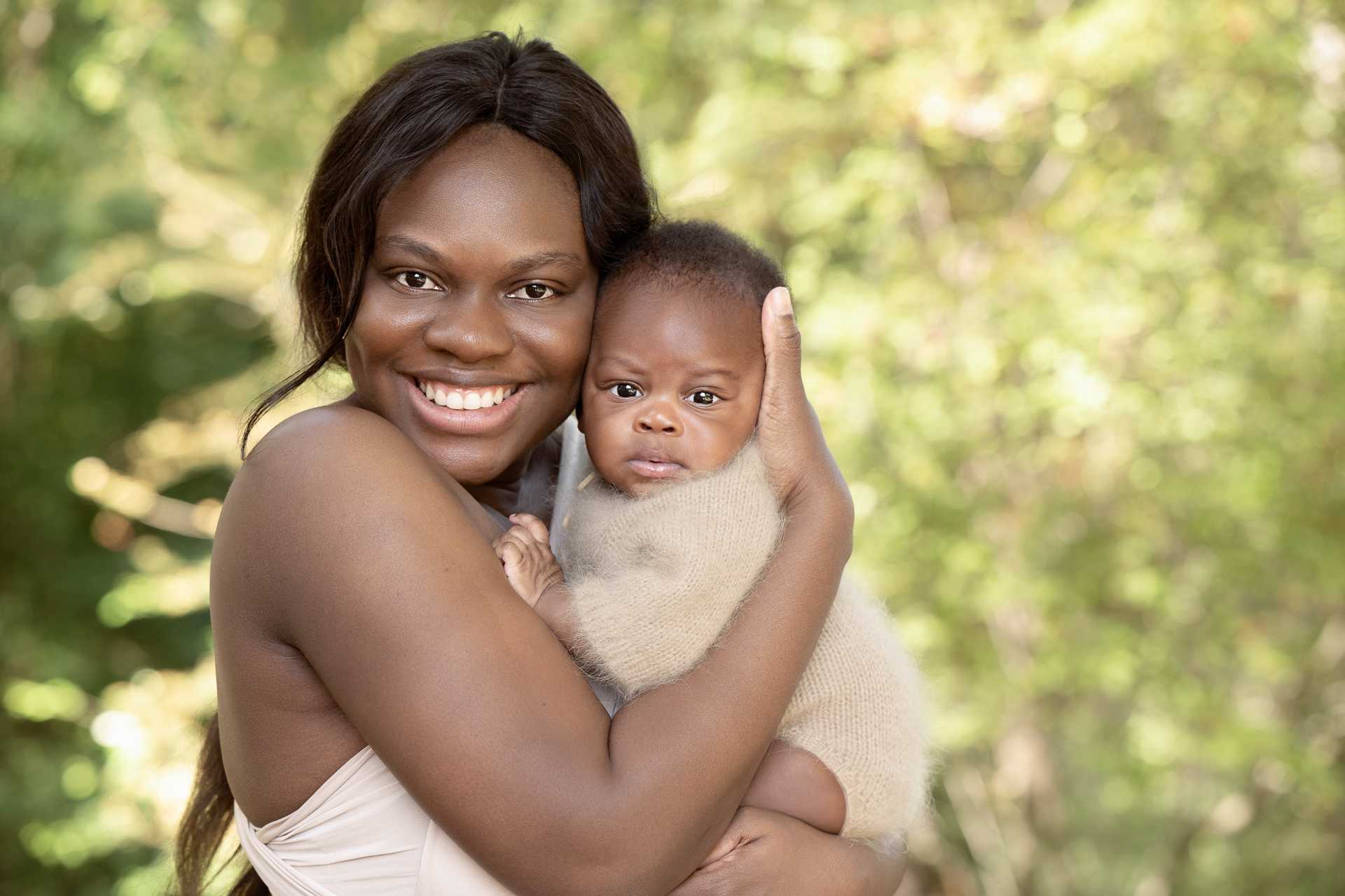 Mother posing outdoors with her newborn son. Both on light brown outfits.