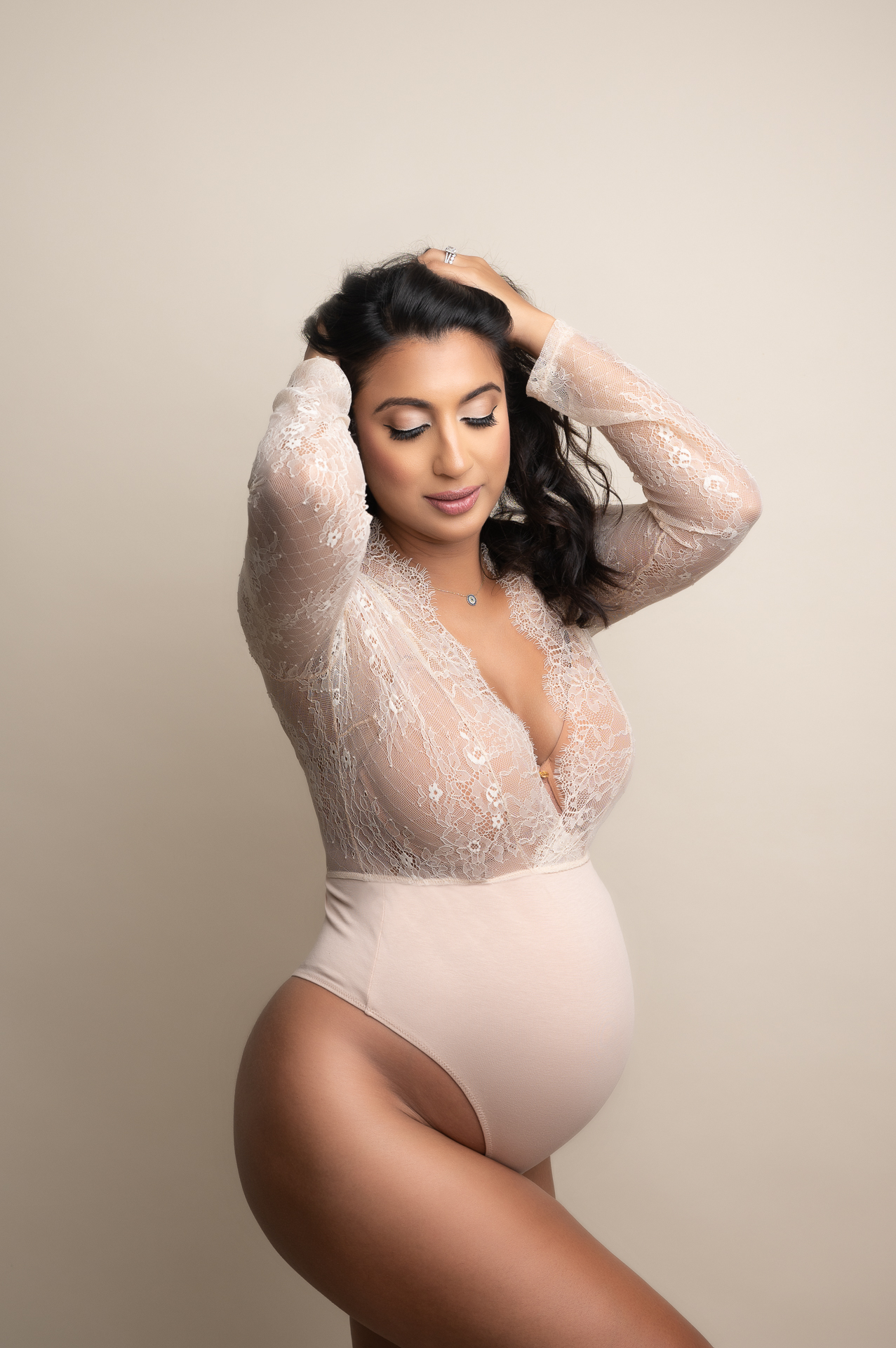 pregnant woman standing wearing a half lace top bodysuit outfit