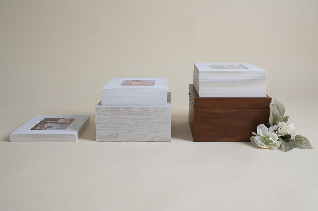 Walnut color box and its stacked white frames on top of it, white color box whit it stacked frames. White frames by itself. Flowers decorating.