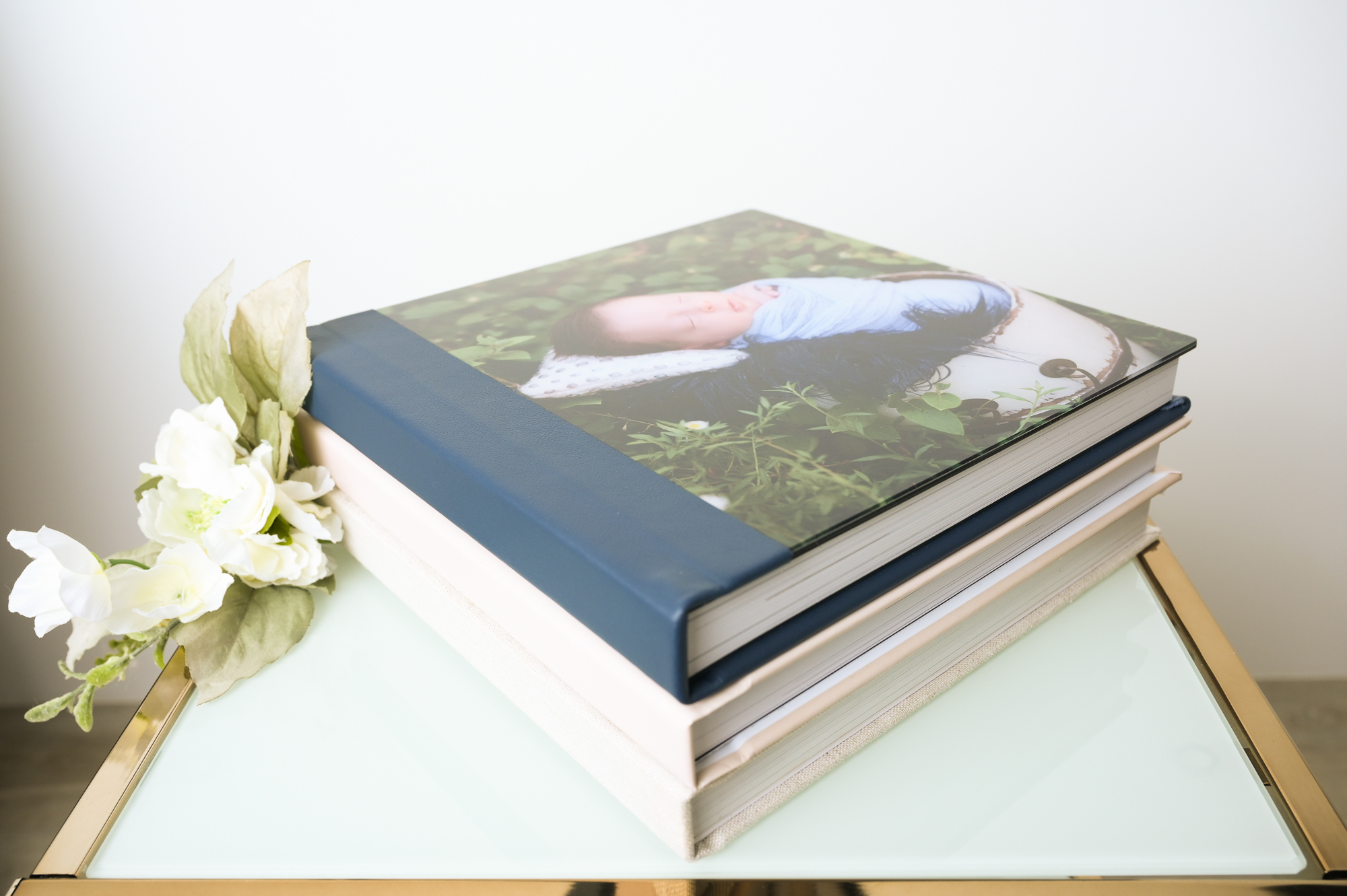 3 newborn photo albums on top of a table