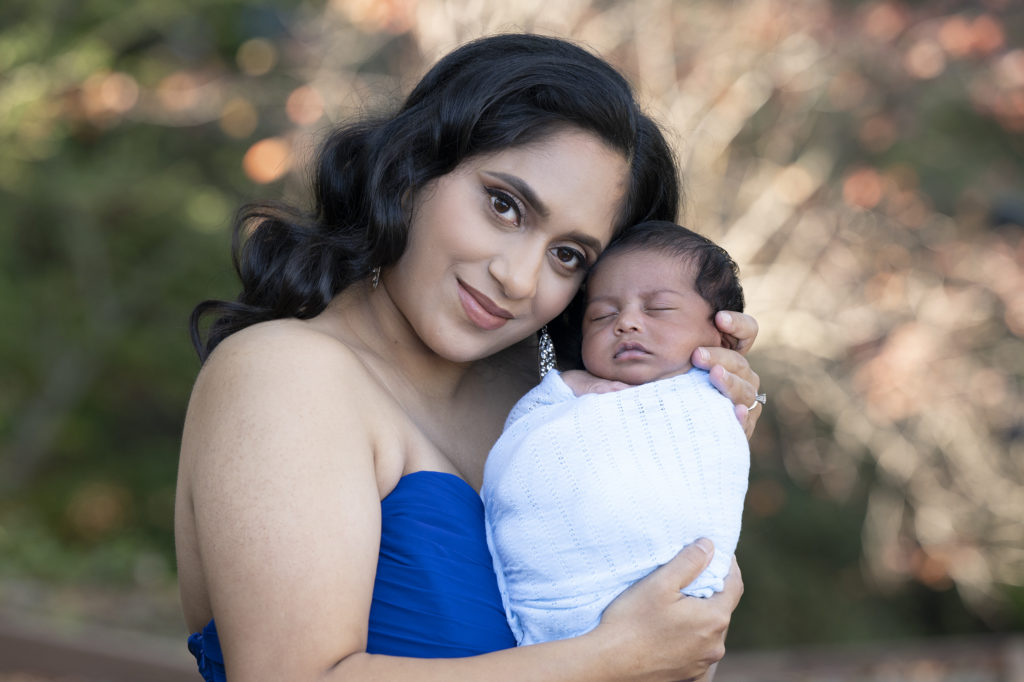 mother and newborn posing outdoors before retouching