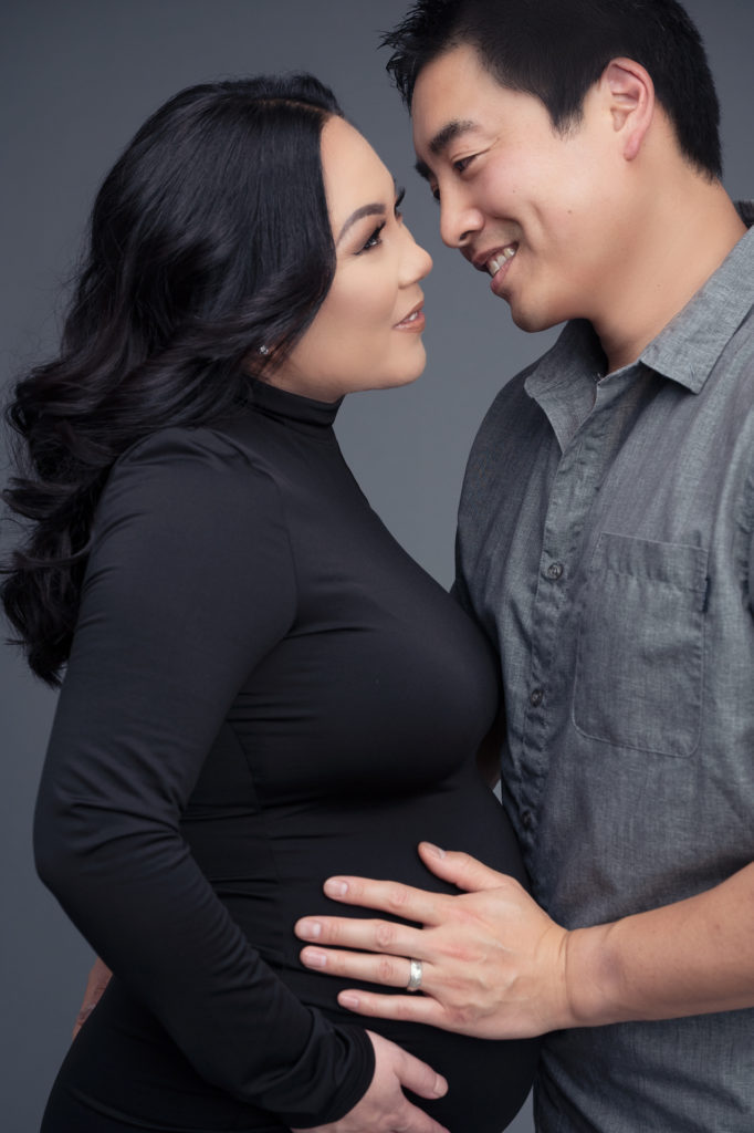 pregnant woman and husband look at each other, they wear a black dress and gray T-shirt