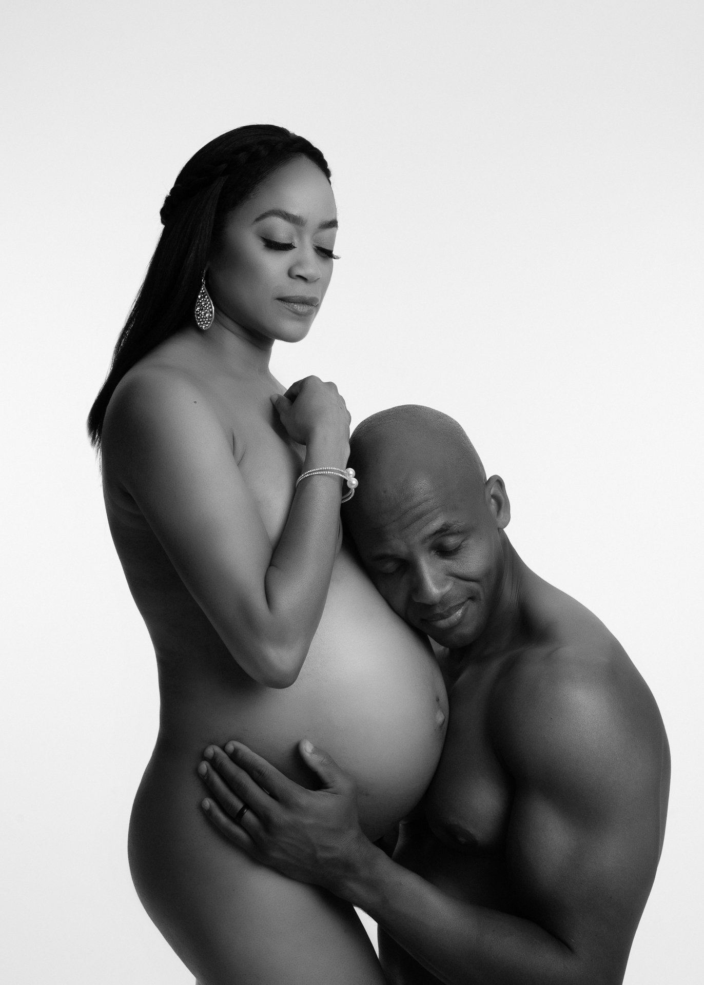 During a maternity photography in the bay area,A pregnant woman and man share a tender moment, hands on her belly. there is implied nudity