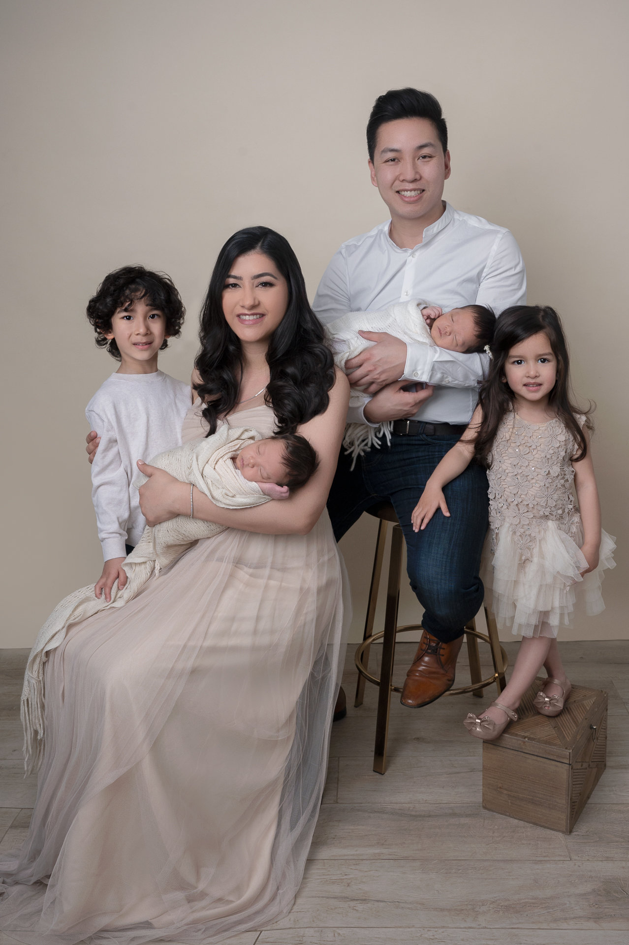 A family portrait featuring a mother, father, and three children, with the mother holding a baby.