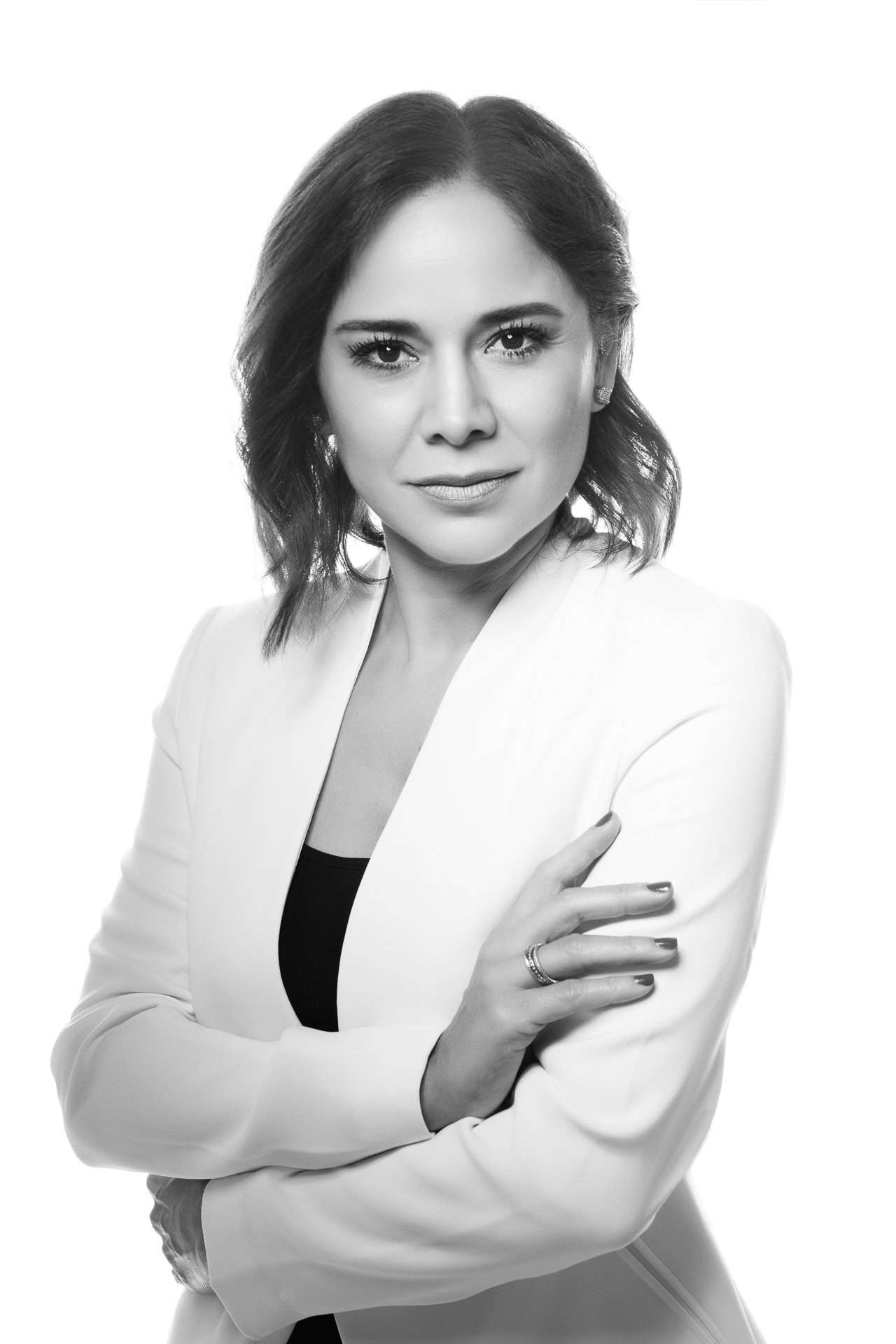 Black and white portrait of a woman in a white blazer, arms crossed, looking directly at the camera during her Personal branding photoshoot.