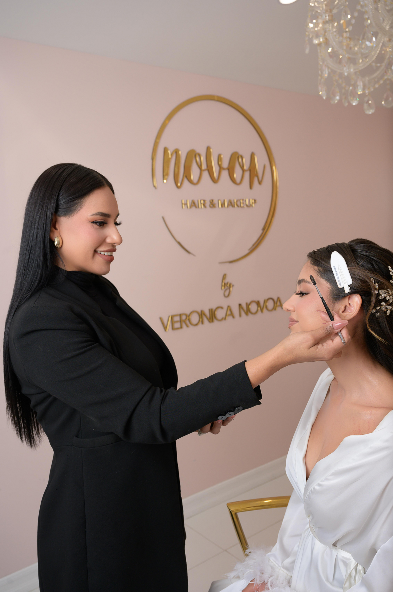 Personal branding session: A makeup artist in black applies makeup to a client in a white robe under the NOVOU Hair & Makeup logo.