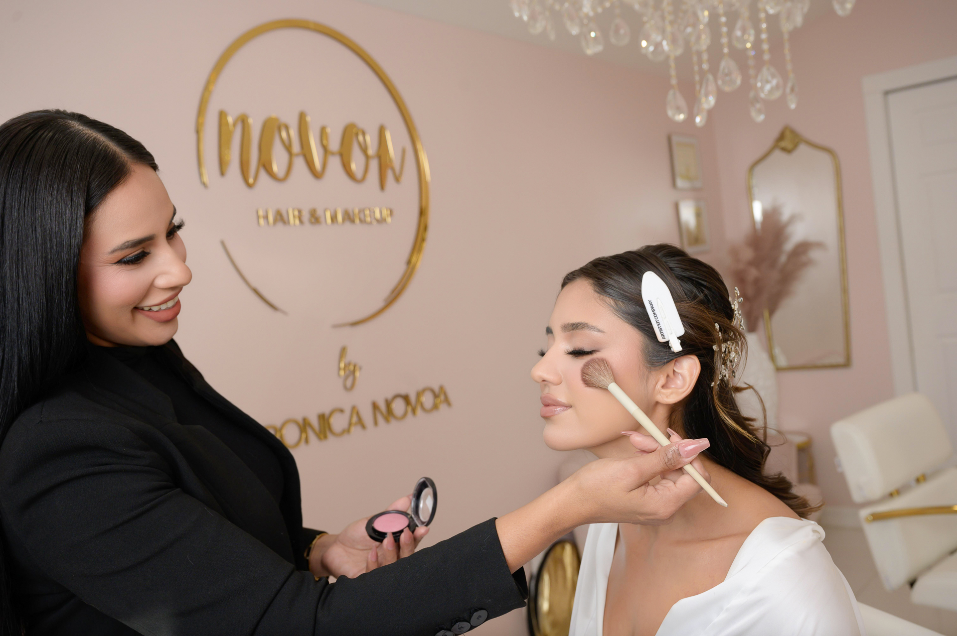 Image by Gaby Clark www.gabyclark.com Personal branding in a San Francisco Bay Area salon—a makeup artist applies blush to a woman’s cheek amid pink walls and gold decor.