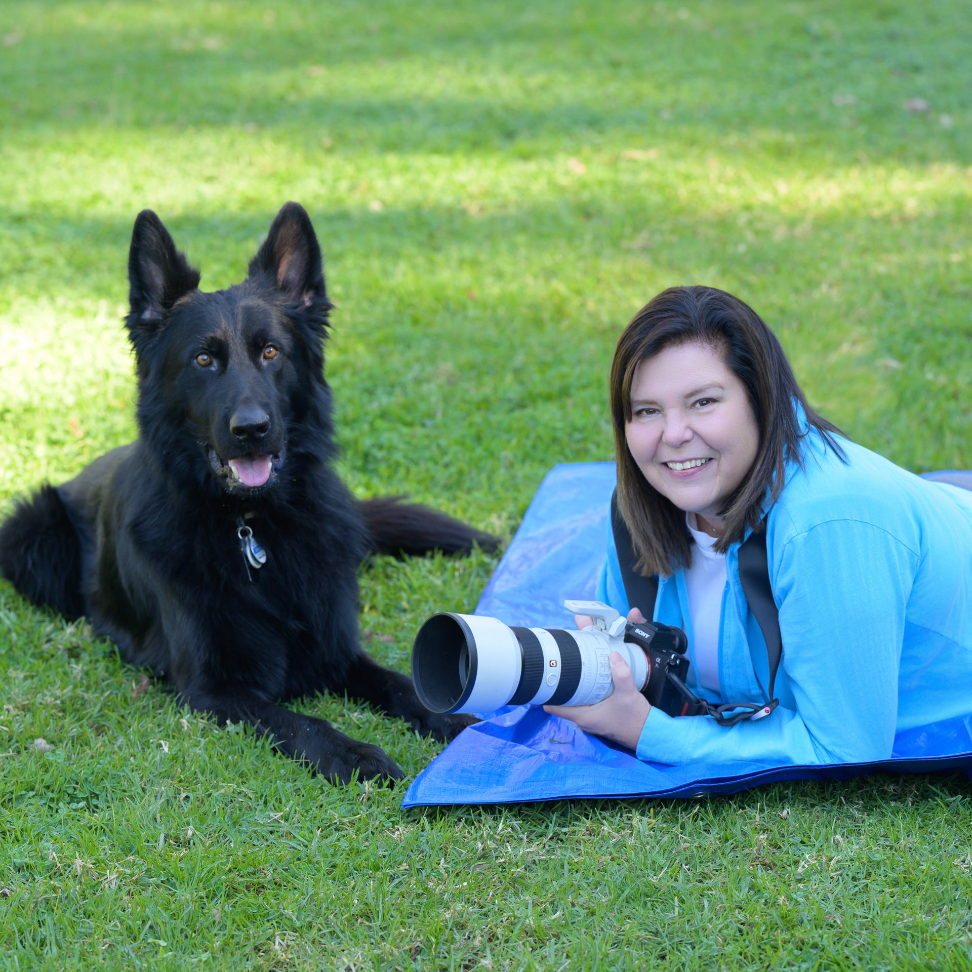 Online Presence Photography: San Jose Pet Photographer personal branding session: A woman lying on a blue mat with a black dog beside her, holding a camera with a large lens.
