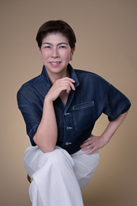 Portrait of a Woman in Denim Shirt A woman wearing a denim shirt and white pants poses with one hand on her chin and the other on her hip.